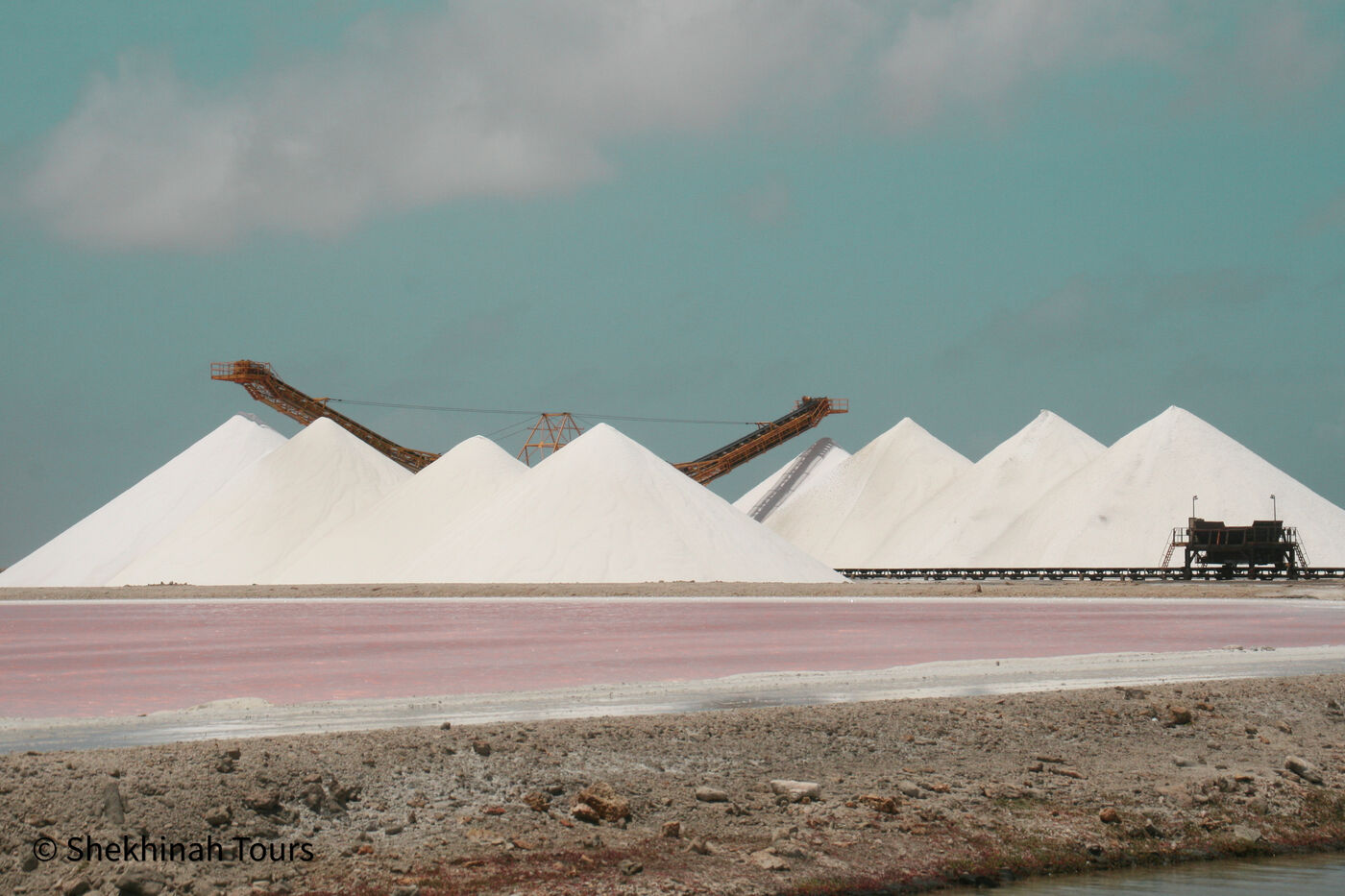 White salt pyramids mirrored in pink water on Bonaire’s south loop